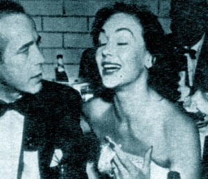Humphrey Bogart with Hjordis Niven, photographed through a telephoto lens at an Oscar night celebration in Romanoff's, 1952.